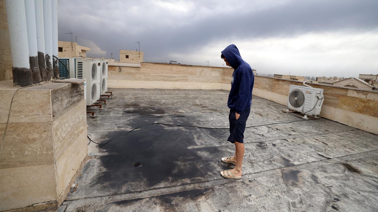 Ein Mann steht auf einem Flachdach und betrachtet eine schwarze Pfütze.