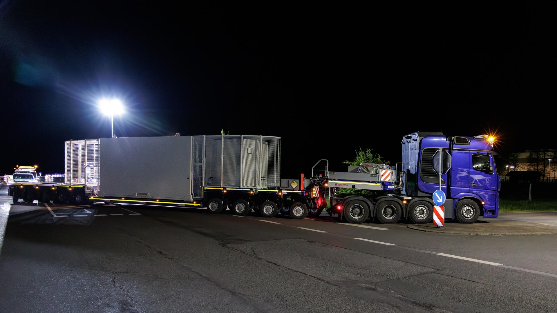 Ein Lastwagen mit einem Castor-Behälter steht quer auf einer Straße.