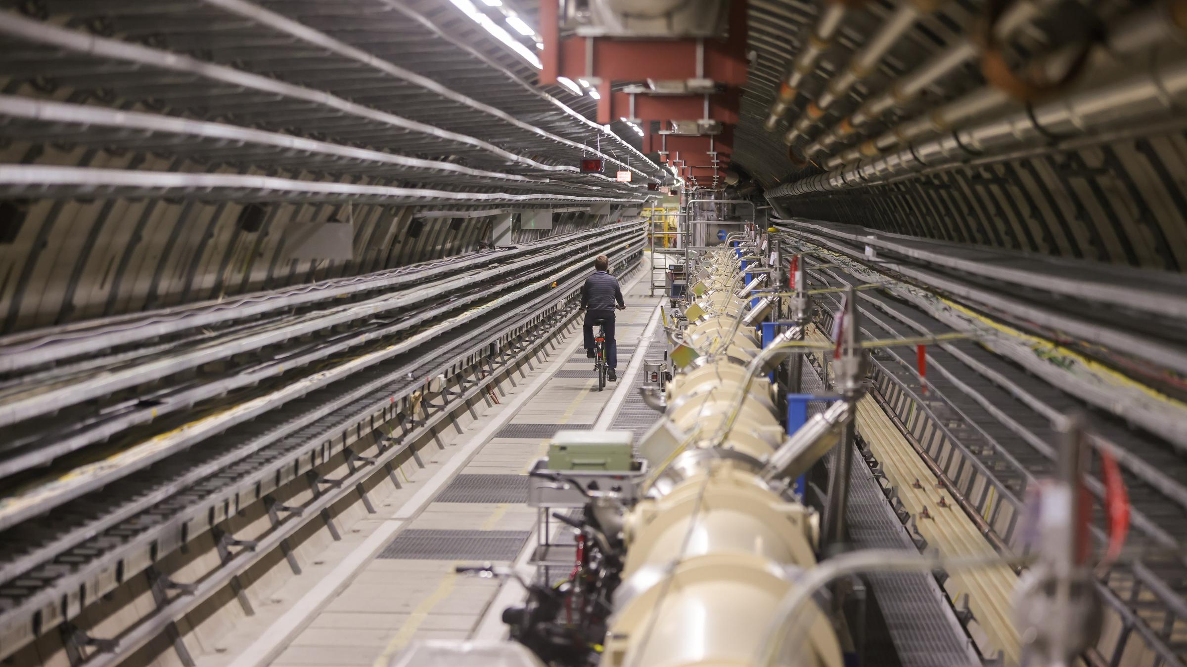 Ein Mitarbeiter im Tunnel neben dem Teilchenbeschleuniger Hera des Deutschen Elektronen-Synchrotron (DESY) in Hamburg. Hera ist ein über sechs Kilometer langer, unterirdischer Ringbeschleuniger, das weltweit präziseste Elektronenmikroskop für die Untersuchung der inneren Struktur des Protons. Forscher wollen Dunkle Materie erkunden. Ein Mitarbeiter im Tunnel neben dem Teilchenbeschleuniger Hera des Deutschen Elektronen-Synchrotron (DESY) in Hamburg. Hera ist ein über sechs Kilometer langer, unterirdischer Ringbeschleuniger, das weltweit präziseste Elektronenmikroskop für die Untersuchung der inneren Struktur des Protons. Forscher wollen Dunkle Materie erkunden.