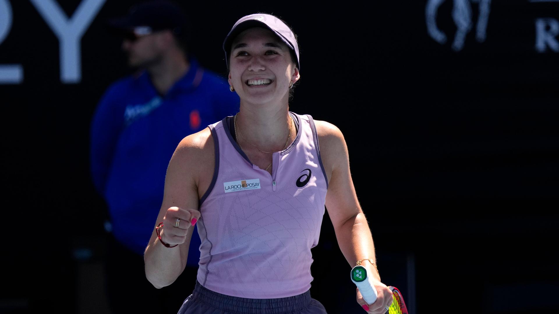 Eine Tennisspielerin hält den Schläger in der einen Hand und ballt die andere hand zur Faust. Sie lacht. Es ist die deutsche Tennis-Spielerin Eva Lys. 