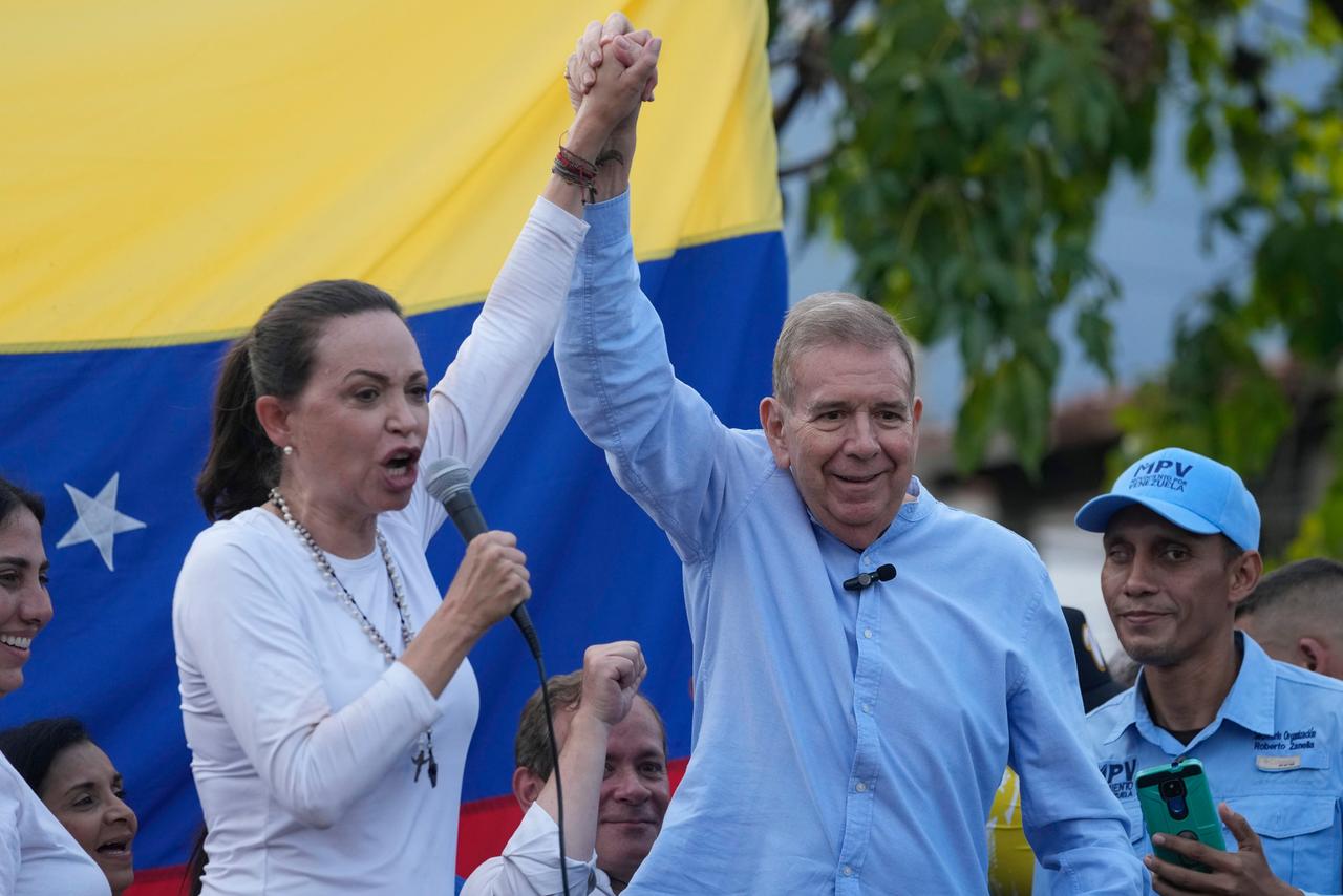 Maria Corina Machado und Edmundo Gonzalez Urrutia recken ihre Hände nach oben. Machado hält ein Mikrofon in die Höhe, im Hintergrund die venezolanische Flagge. Maria Corina Machado und Edmundo Gonzalez Urrutia recken ihre Hände nach oben. Machado hält ein Mikrofon in die Höhe, im Hintergrund die venezolanische Flagge.