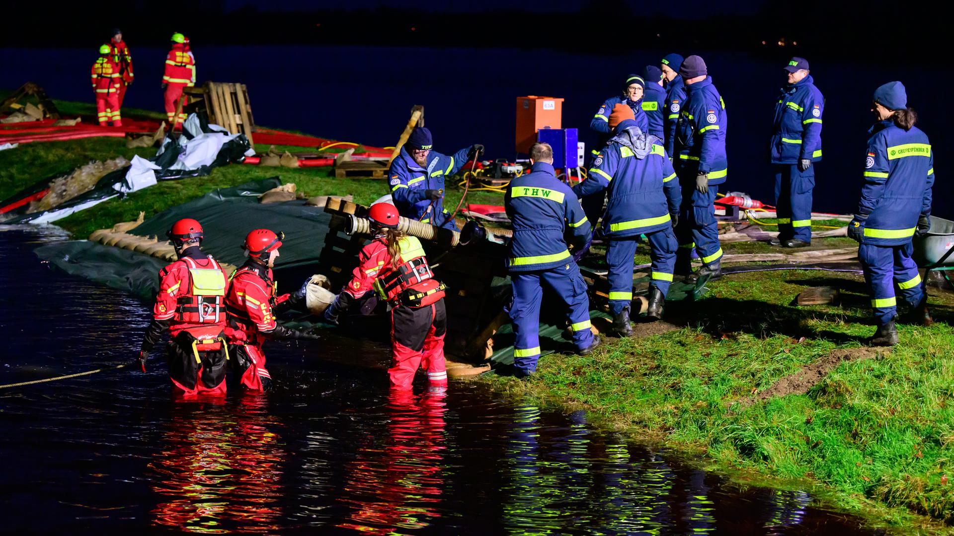 Einsatzkräfte vom THW und der DLRG befestigen einen Deich im niedersächsischen Hodenhagen.