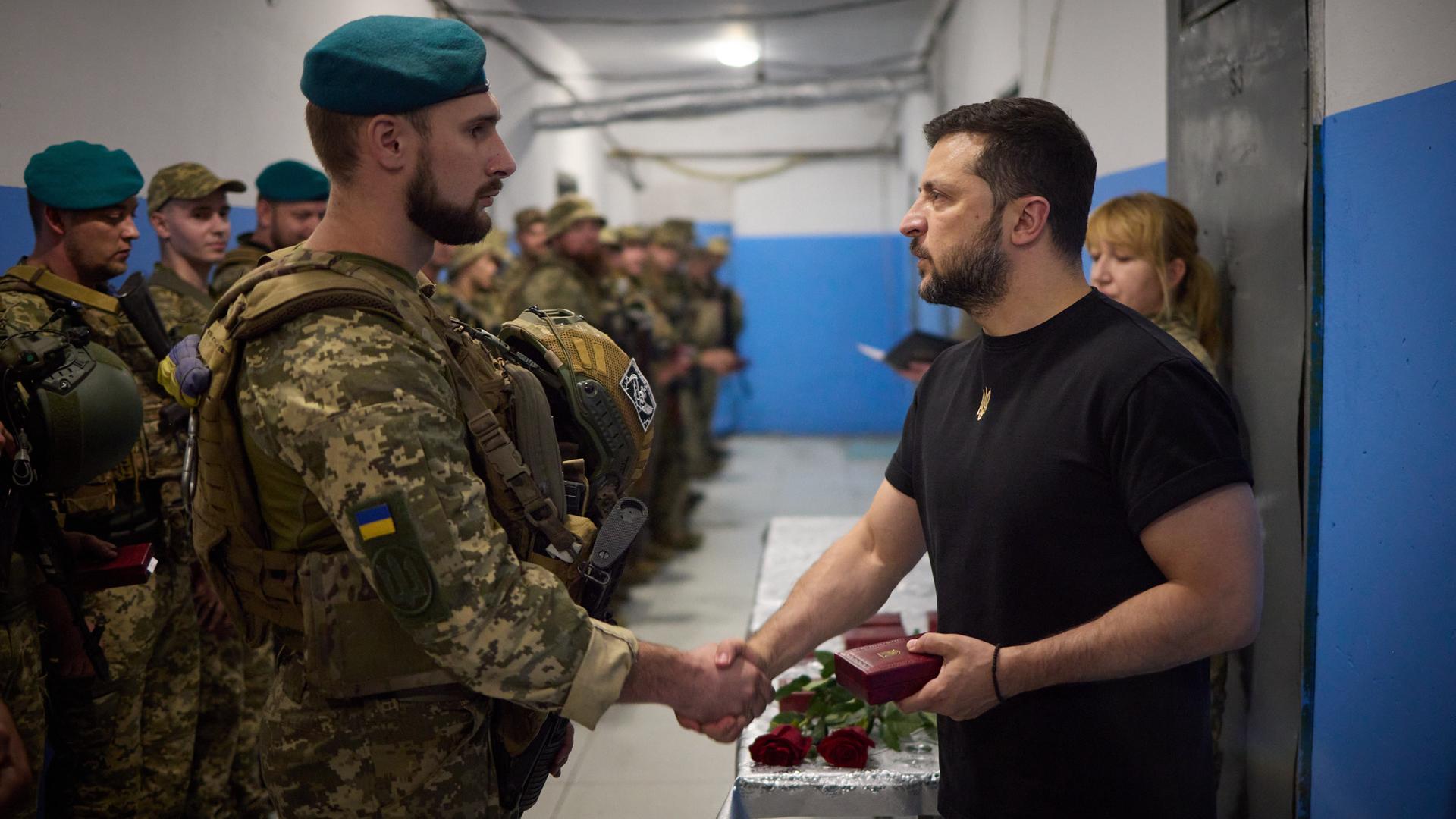 Der ukrainische Präsident Wolodymyr Selenskyj schüttelt einem Soldaten die Hand. Er besucht Truppen an der Südfront. 
