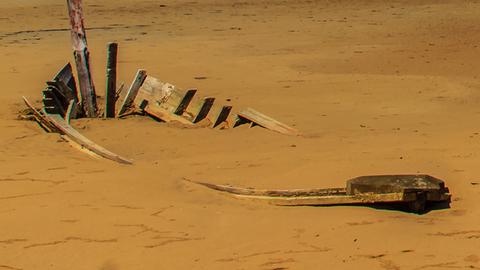 Das Gerippe eines Bootes im Sand.