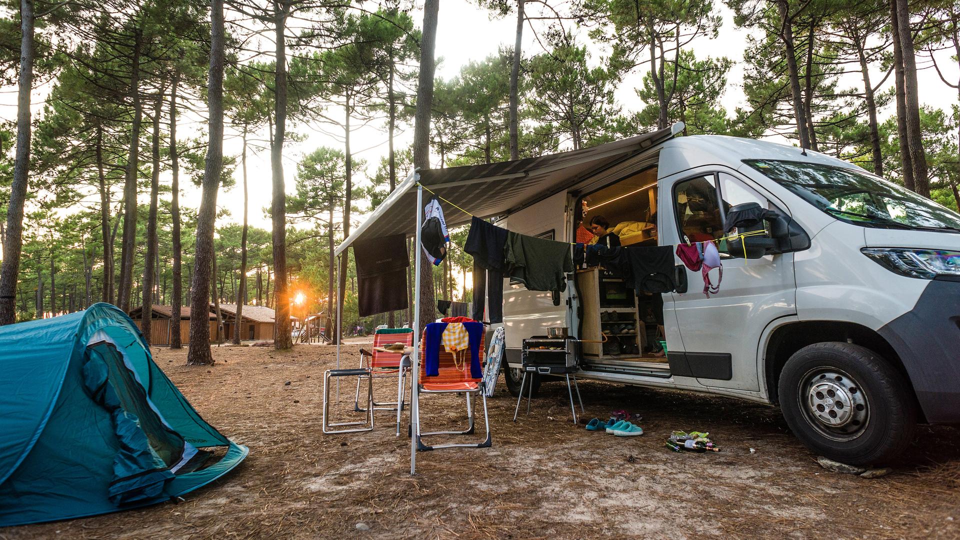 Ein gedeckter Tisch mit Campingstühlen steht vor einem Wohnmobil auf einem Campingplatz bei Bordeaux Ein gedeckter Tisch mit Campingstühlen steht vor einem Wohnmobil auf einem Campingplatz bei Bordeaux