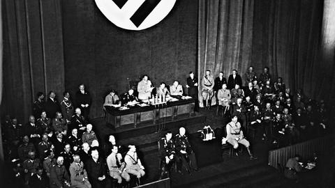 Ein historisches Schwarz-Weiß-Foto zeigt eine Reichstagssitzung am 15.09.1935 in Nürnberg. Hermann Göring steht in der Bildmitte hinten am Rednerpult.