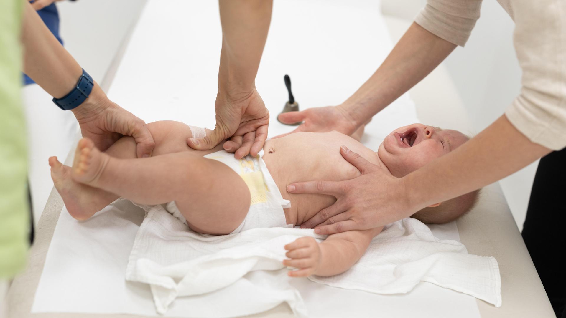 Ein Baby erhält ein Pflaster nach einer Impfung in den Oberschenkel Ein Baby erhält ein Pflaster nach einer Impfung in den Oberschenkel