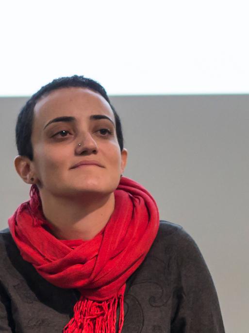 Lina Attalah, die Chefredakteurin der Nachrichtenseite Mada Masr, trägt bei einer Podiumsdiskussion einen Pullover und roten Schal 