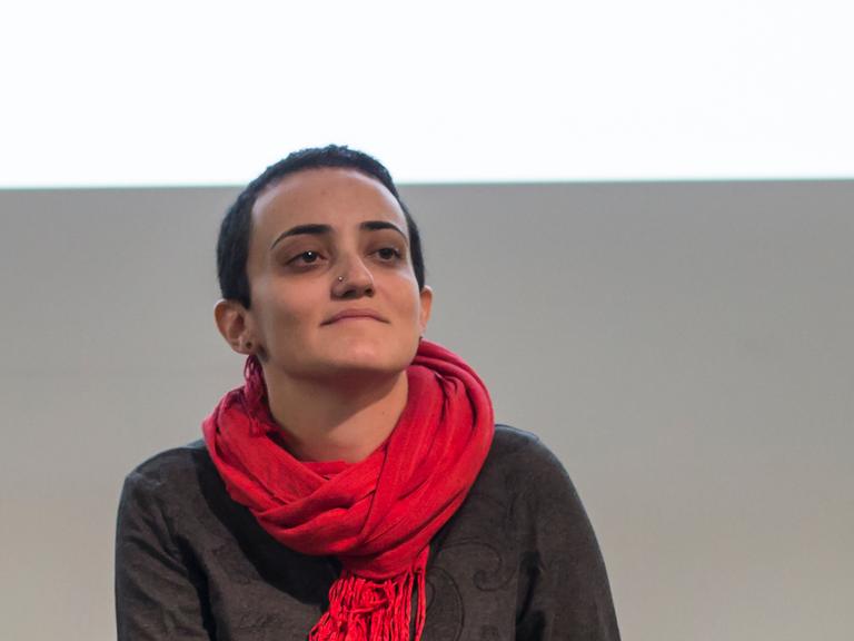 Lina Attalah, die Chefredakteurin der Nachrichtenseite Mada Masr, trägt bei einer Podiumsdiskussion einen Pullover und roten Schal 