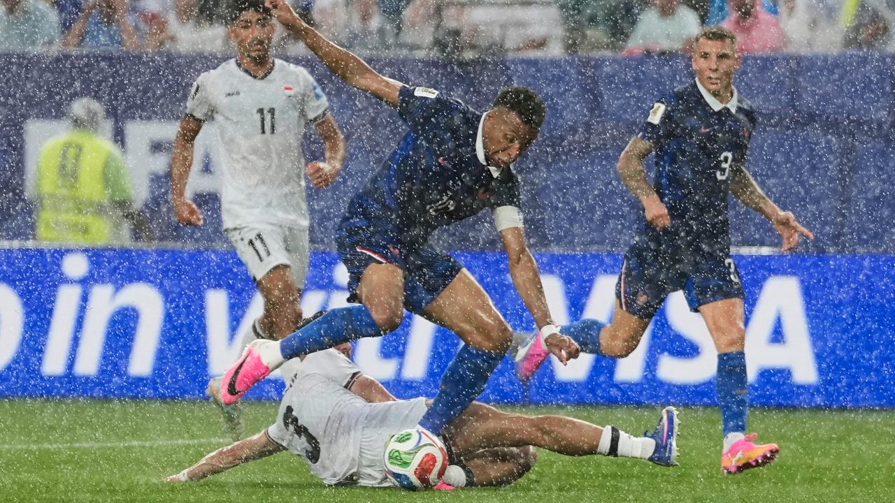 Das Bild zeigt meherere Fußballer im Kampf um den Ball bei kräftigem Regen.