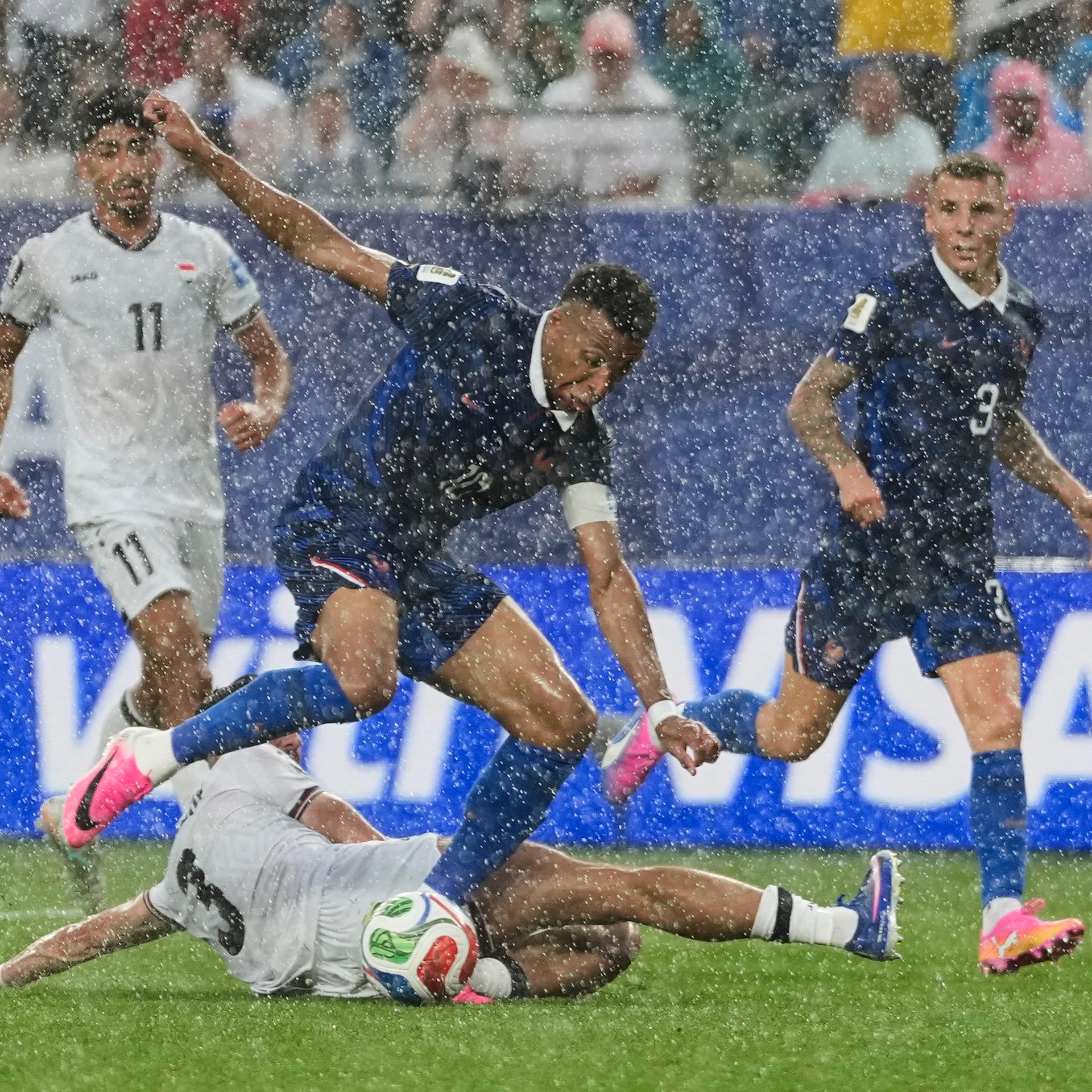 Das Bild zeigt meherere Fußballer im Kampf um den Ball bei kräftigem Regen.