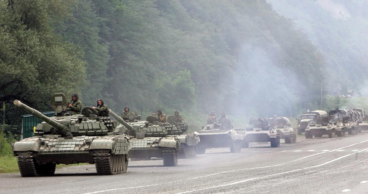 Ein Panzerkonvoi fährt eine Straße entlang. 