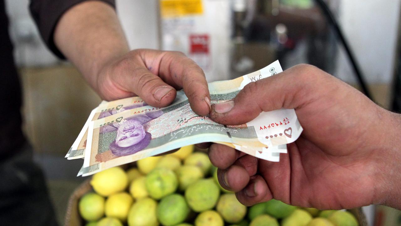 Ein Mann bezahlt in Teheran mit der iranischen Währung Rial.