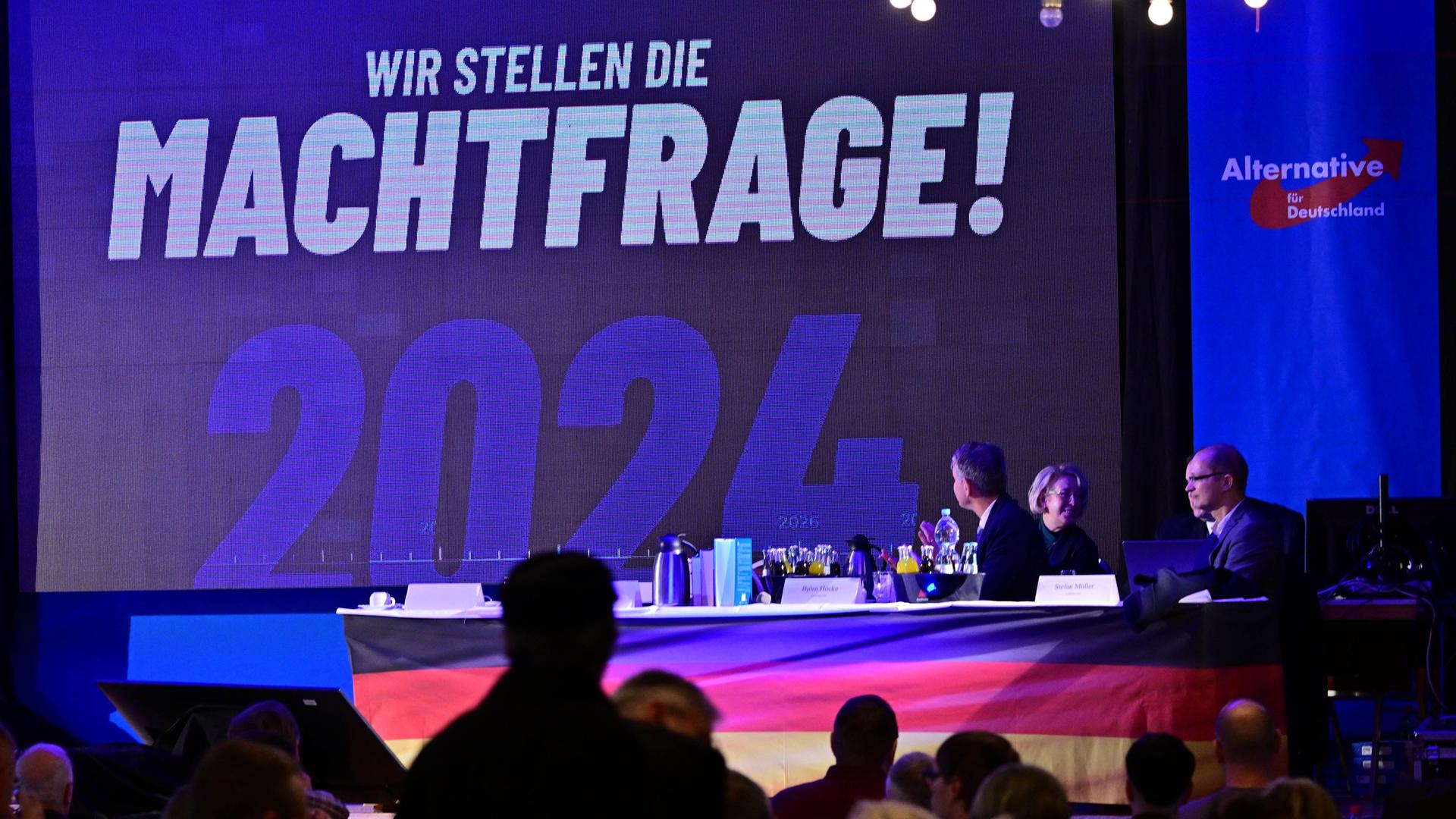 Auf einer Leinwand steht die Aufschrift "Wir stellen die Machtfrage! 2024", daneben das Logo der AfD Thüringen.