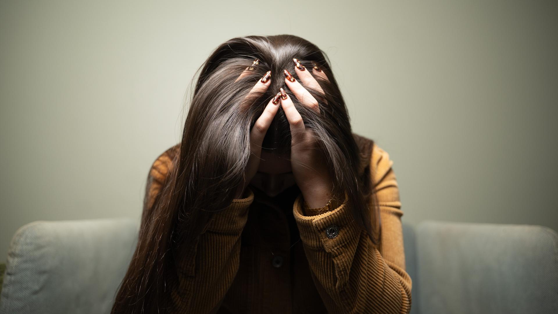 Eine Frau trauert und verbirgt ihr Gesicht hinter Haaren und Händen.