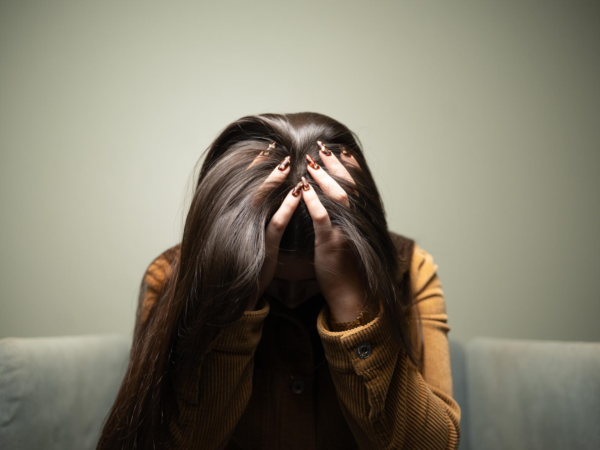 Eine Frau trauert und verbirgt ihr Gesicht hinter Haaren und Händen.