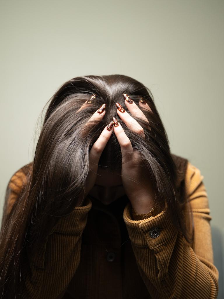 Eine Frau trauert und verbirgt ihr Gesicht hinter Haaren und Händen.