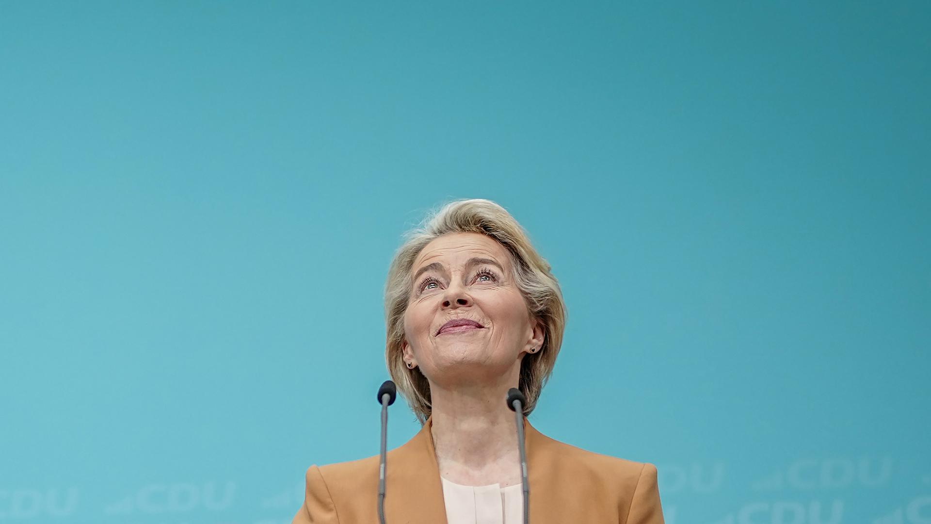 Eine blonde Frau, Ursula von der Leyen, Präsidentin der Europäischen Kommission, blickt nach oben und lächelt.