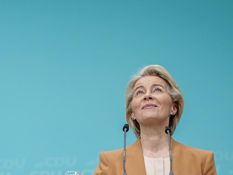 Eine blonde Frau, Ursula von der Leyen, Präsidentin der Europäischen Kommission, blickt nach oben und lächelt.