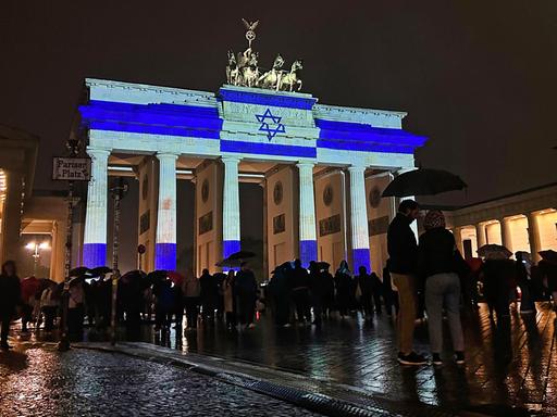 Zu sehen ist das Brandenburger Tor bei Nacht. Es wird hell in den Farben der blau-weißen Flagge Israels angestrahlt