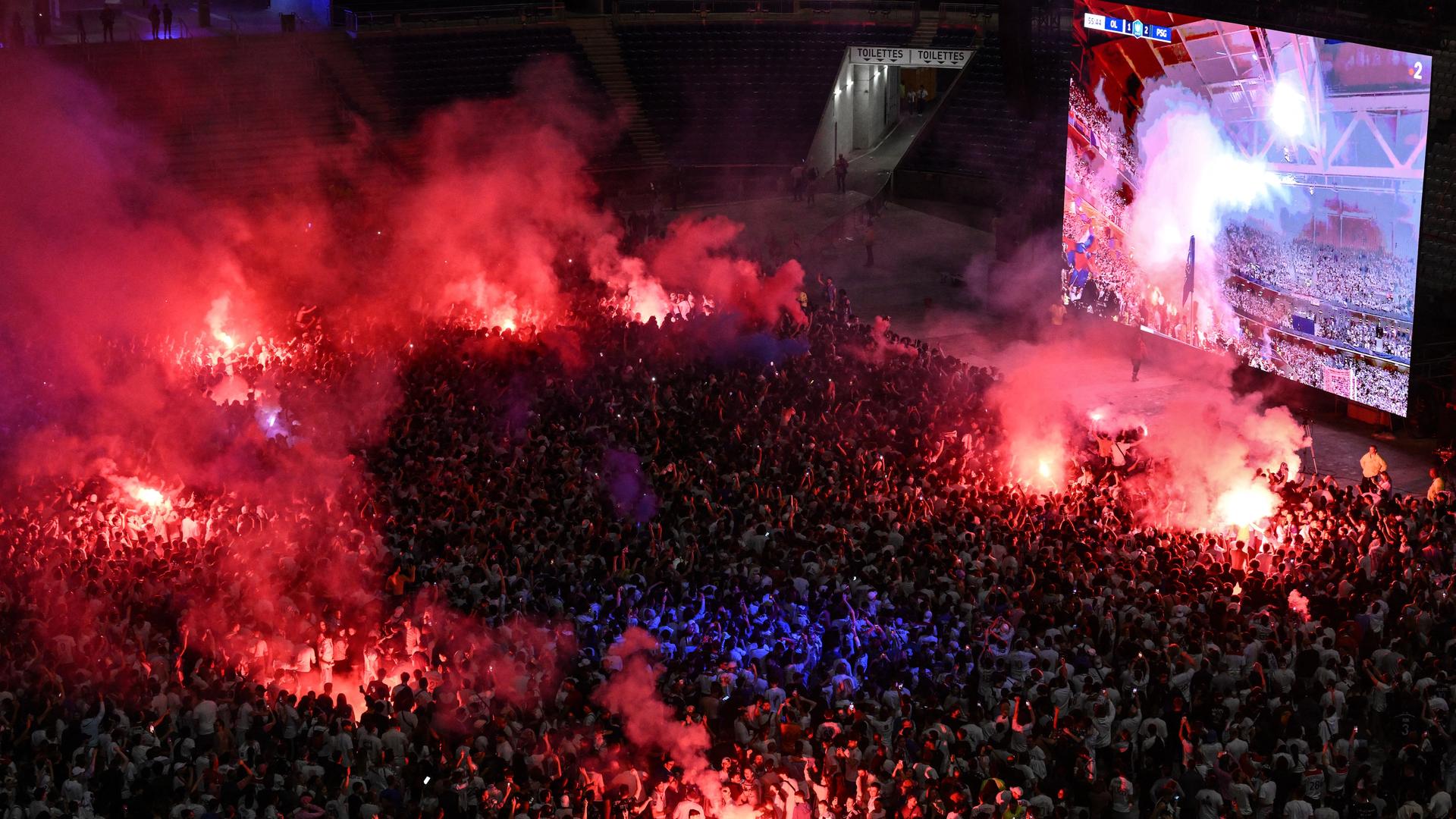 Blick auf die Menschen in einer Fanzone in Lyon. Einige von ihnen haben rote Bengalos angezündet, Rauch steigt auf. Blick auf die Menschen in einer Fanzone in Lyon. Einige von ihnen haben rote Bengalos angezündet, Rauch steigt auf.