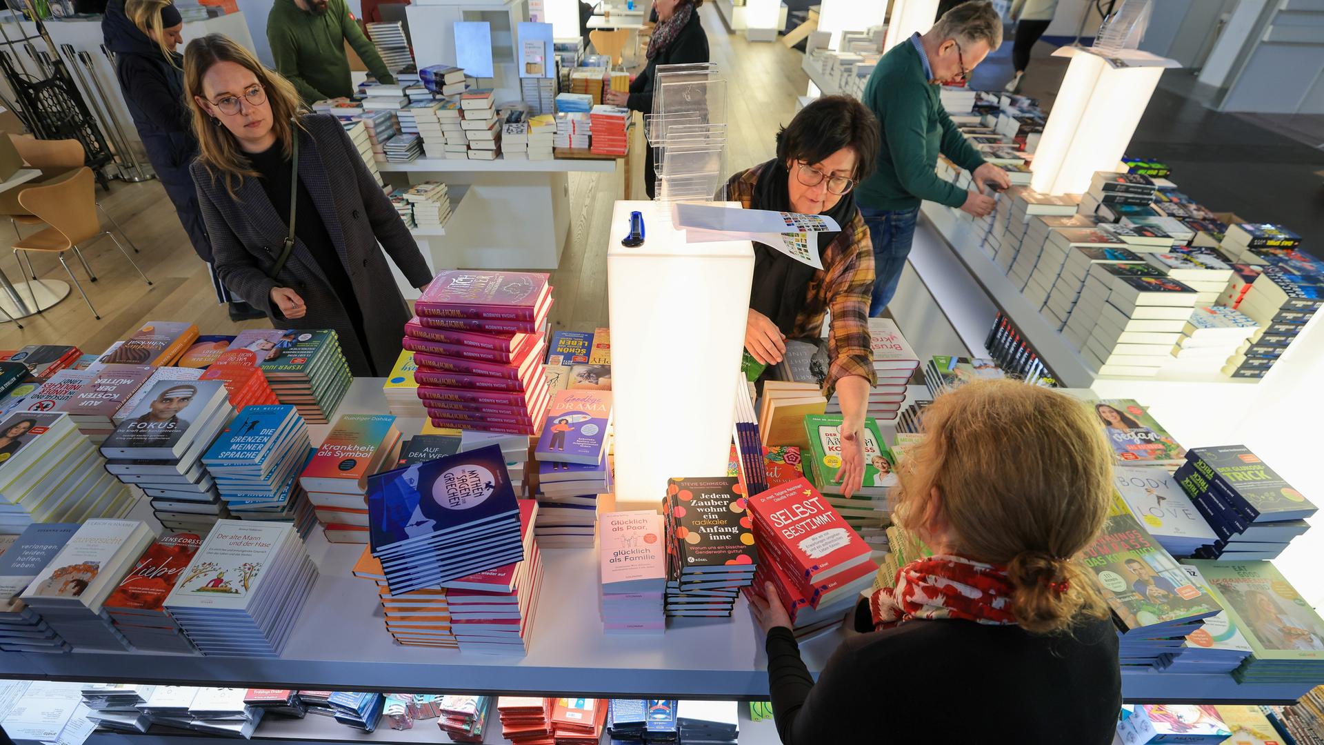 Mitarbeiterinnen und Mitarbeiter sortieren Bücher am Stand von Random House für die Buchmesse. 