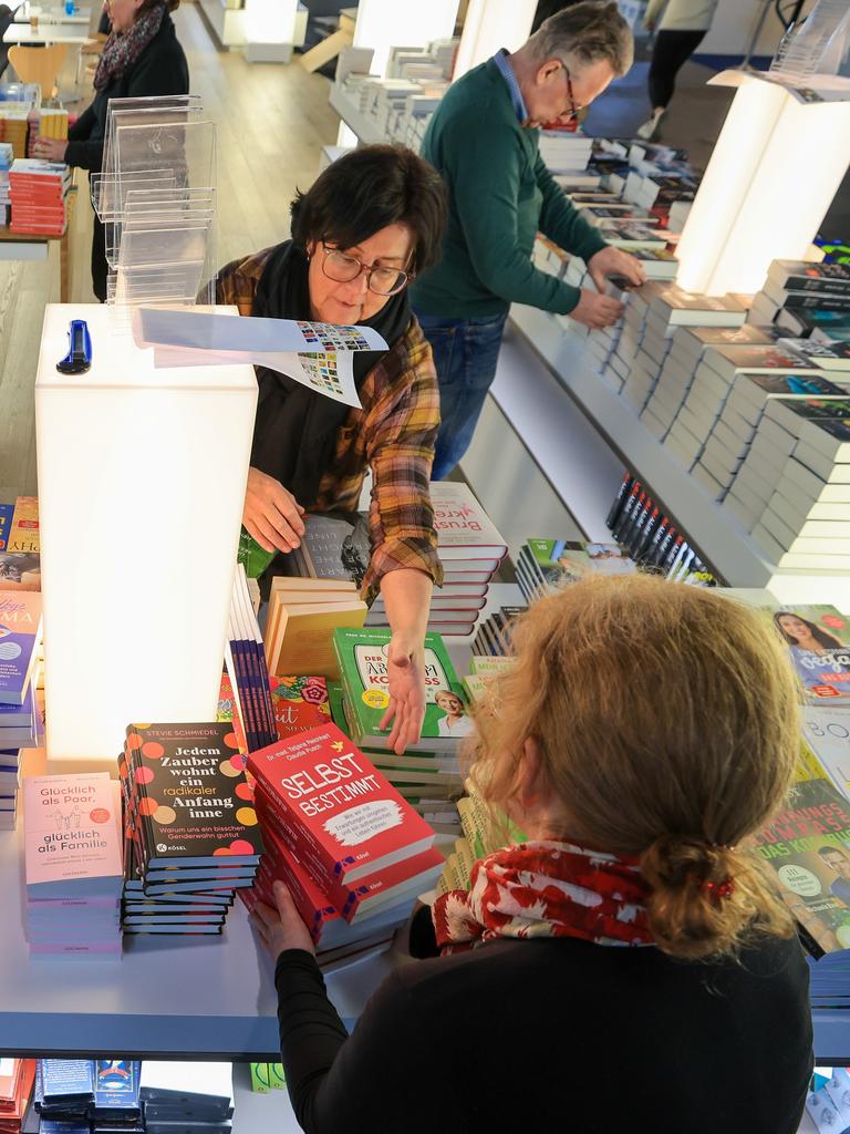 Mitarbeiterinnen und Mitarbeiter sortieren Bücher am Stand von Random House für die Buchmesse. 