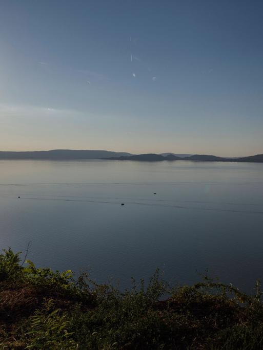 Das Bild blickt von der südlichen Seite auf den Plattensee. Der Himmel ist blau, anhand des Sonnenstandes kann man vom späten Nachmittag im Sommer ausgehen. 