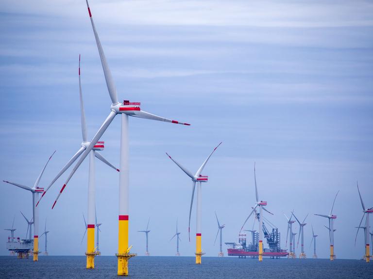 Ein Arbeitsschiff steht auf Stelzen zwischen den Windrädern die in der Ostsee. Im Vordergrund ist der Windpark "Arkona" etwa 35 Kilometer nordöstlich von Rügen zu sehen. Im Hintergrund die Offshore-Windkraftanlagen des Ostsee-Windpark "Wikinger"