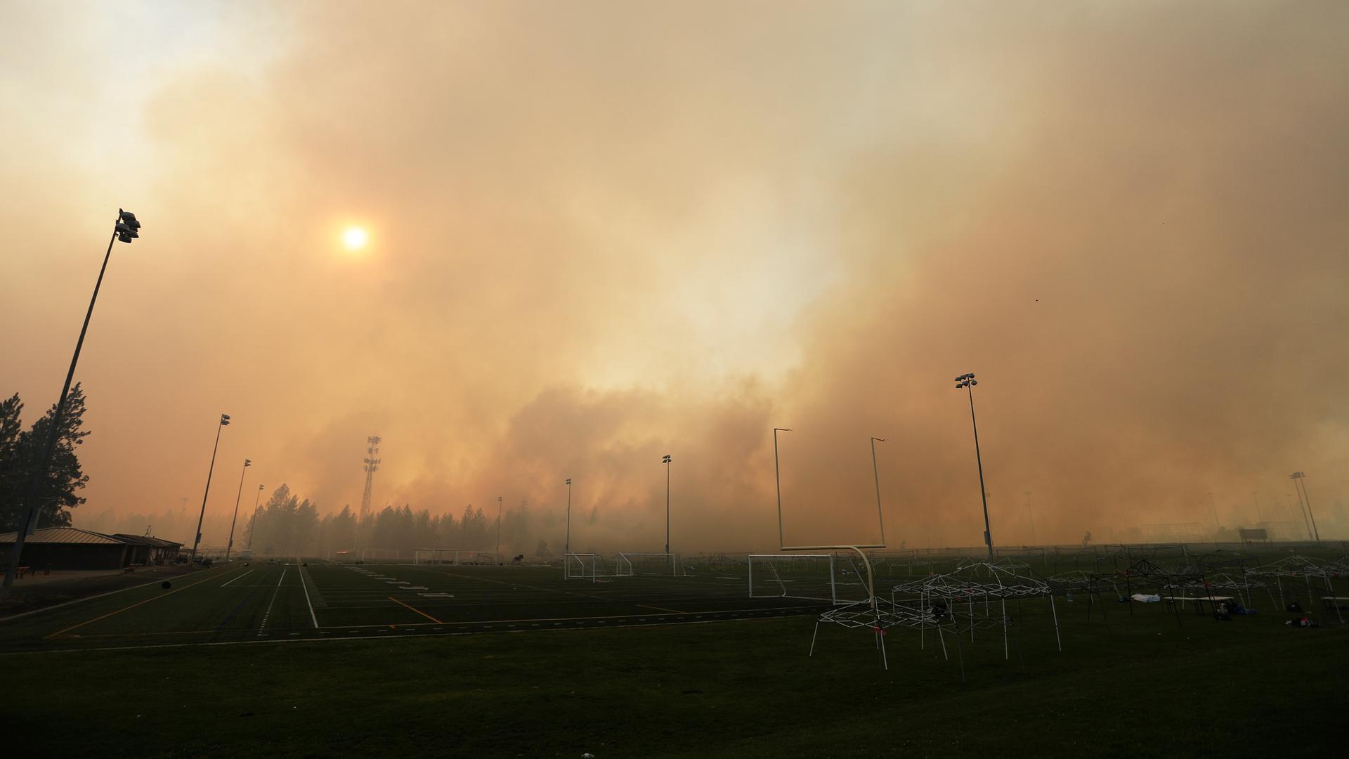 Qualm und Rauch von einem Brand an einer Straße. Die Sonne ist durch den Schleier kaum noch zu sehen. Qualm und Rauch von einem Brand an einer Straße. Die Sonne ist durch den Schleier kaum noch zu sehen.
