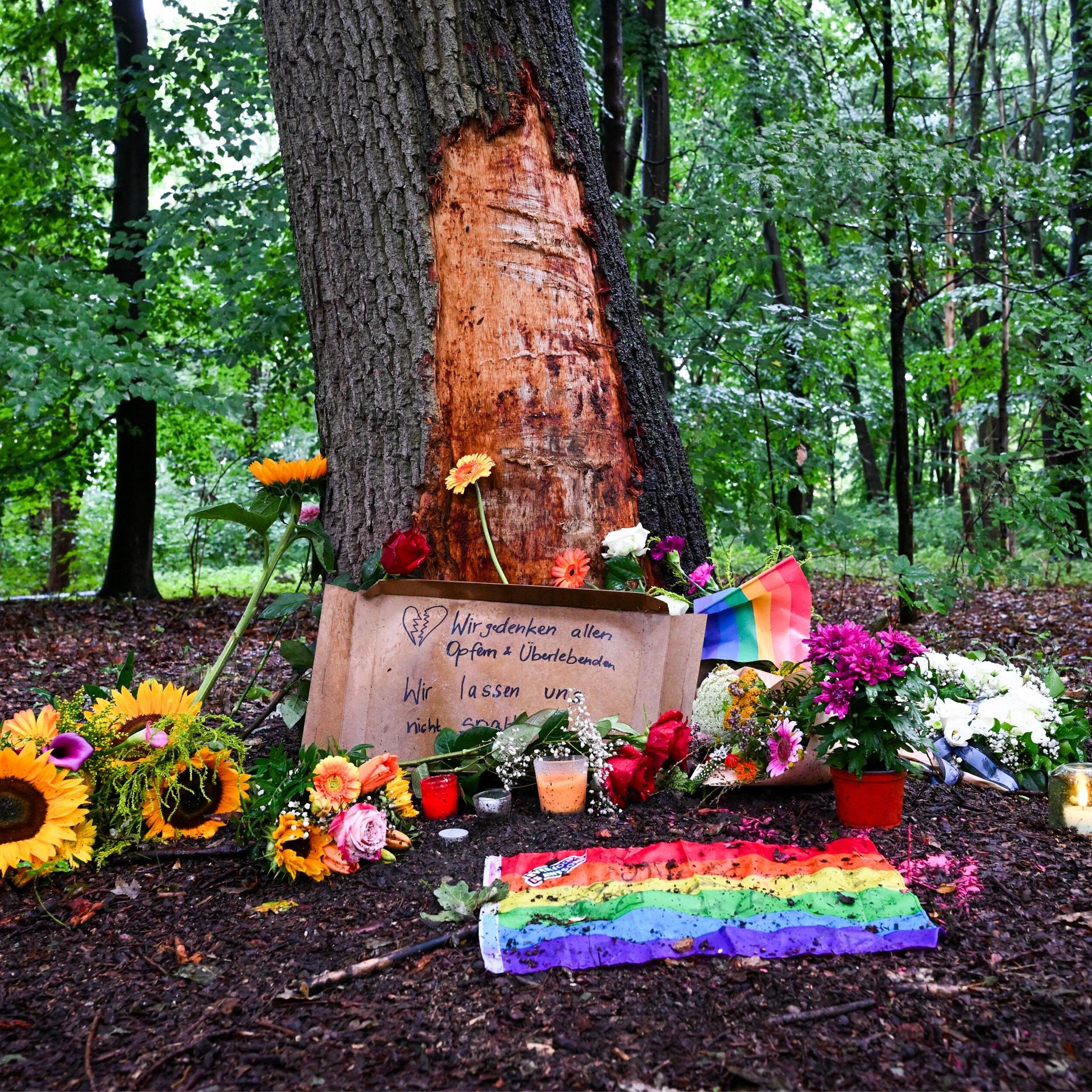 Blumen, Kerzen und die Botschaft „Wir gedenken aller Opfer und Überlebenden“ sind am Morgen an einem Baum mit beschädigter Rinde zu sehen, wo ein Fahrzeug am Rande des Christopher Street Day in eine Menschenmenge gefahren war.