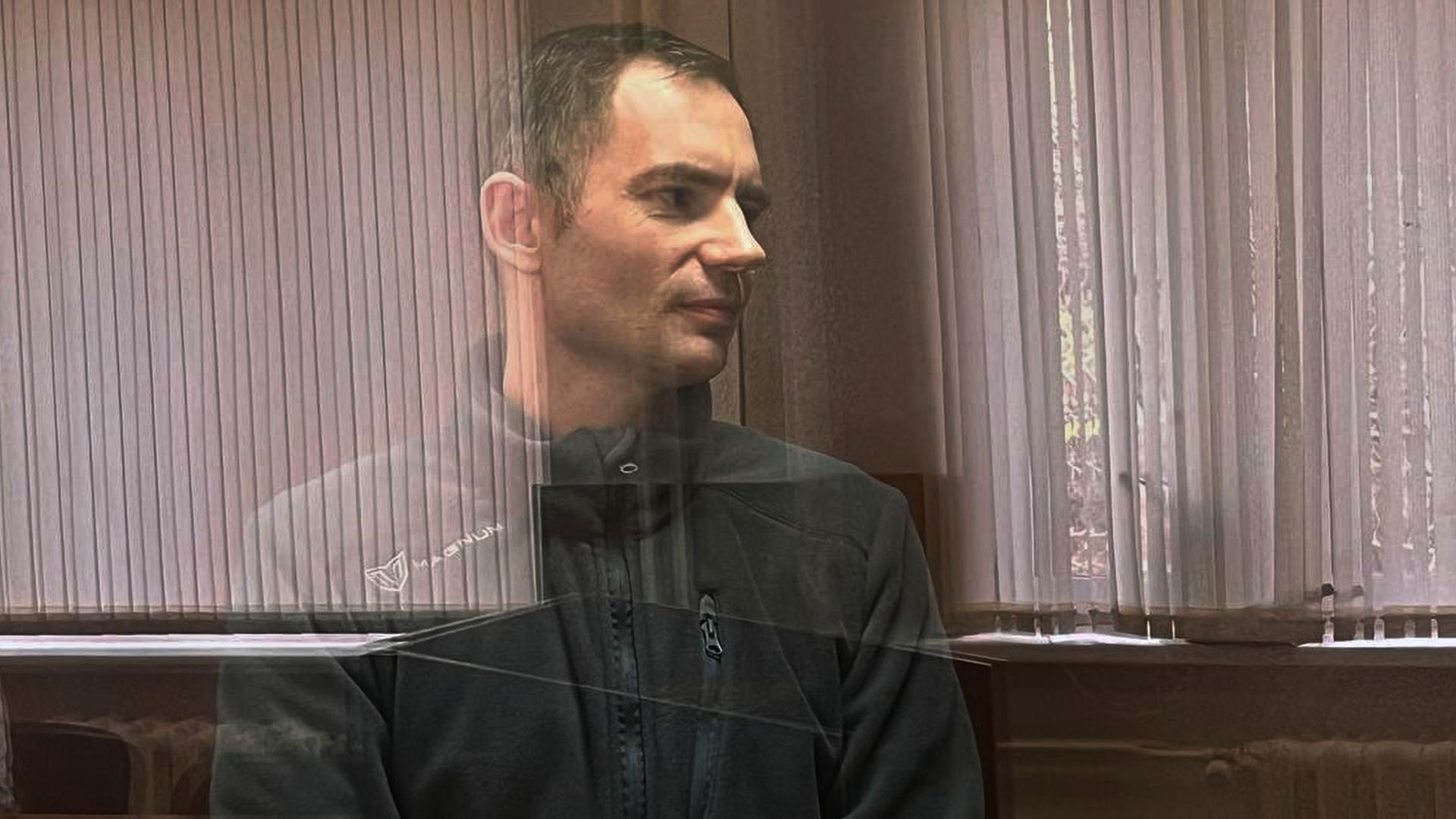 Das Foto zeigt Maxim Kruglow in einem Gerichtssal hinter einer Glasscheibe.