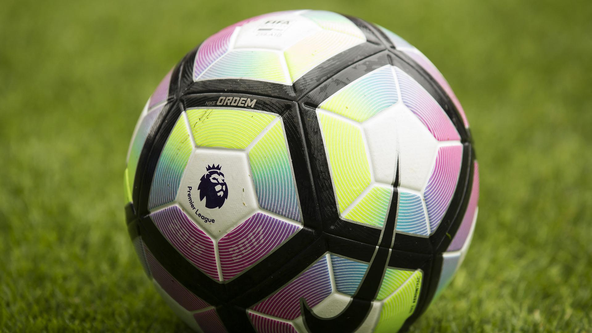 Das Logo der Premier League auf einem Fußball, der auf dem Rasen eines Stadions liegt.