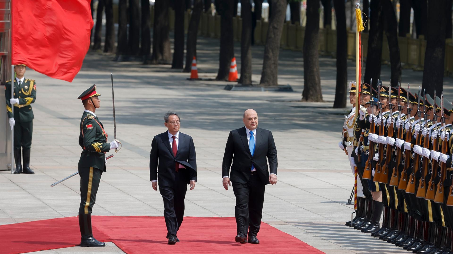 China, Peking: Michail Mischustin (M, r), Ministerpräsident von Russland, und Li Qiang, Ministerpräsident von China, nehmen an einer Begrüßungszeremonie teil.