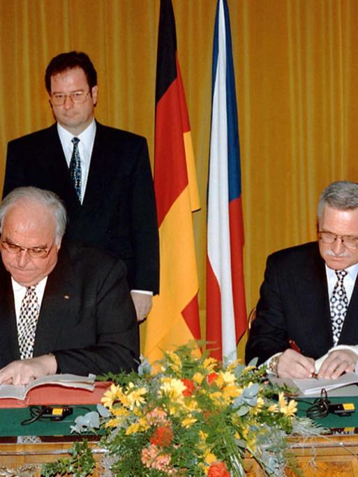 Bundeskanzler Helmut Kohl (l) und der tschechische Ministerpräsident Vaclav Klaus sitzen an einem Tisch und unterzeichnen Verträge  