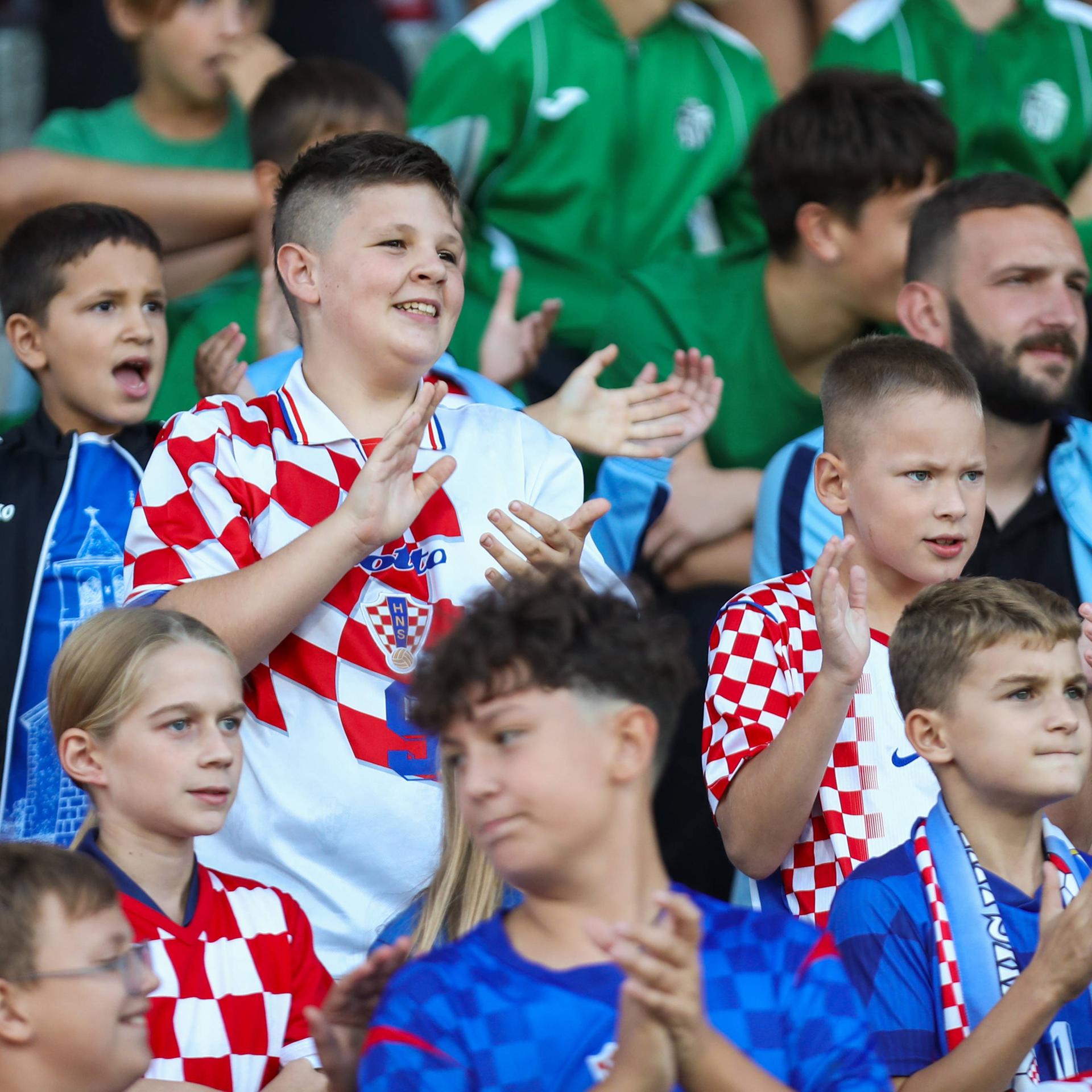 Kinder mit kroatischen Trikots und Schals auf der Tribüne.