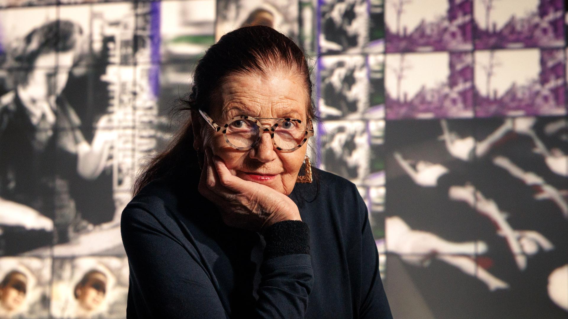 Ulrike Rosenbach sitzt vor ihrem Werk "Das Bild der Frau in der Nachkriegszeit" und blickt freundlich in die Kamera