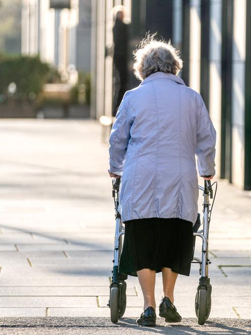 Eine Seniorin läuft am Rollator durch eine Fussgängerzone. (Rückenansicht) Eine Seniorin läuft am Rollator durch eine Fussgängerzone. (Rückenansicht)