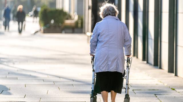 Eine alte Frau läuft am Rollator durch eine Fussgänger-Zone.