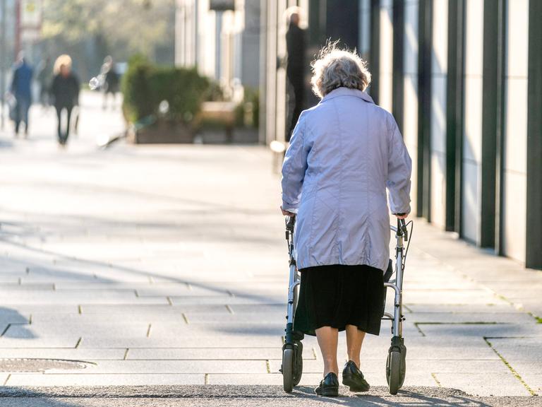 Eine Seniorin läuft am Rollator durch eine Fussgängerzone. (Rückenansicht) Eine Seniorin läuft am Rollator durch eine Fussgängerzone. (Rückenansicht)
