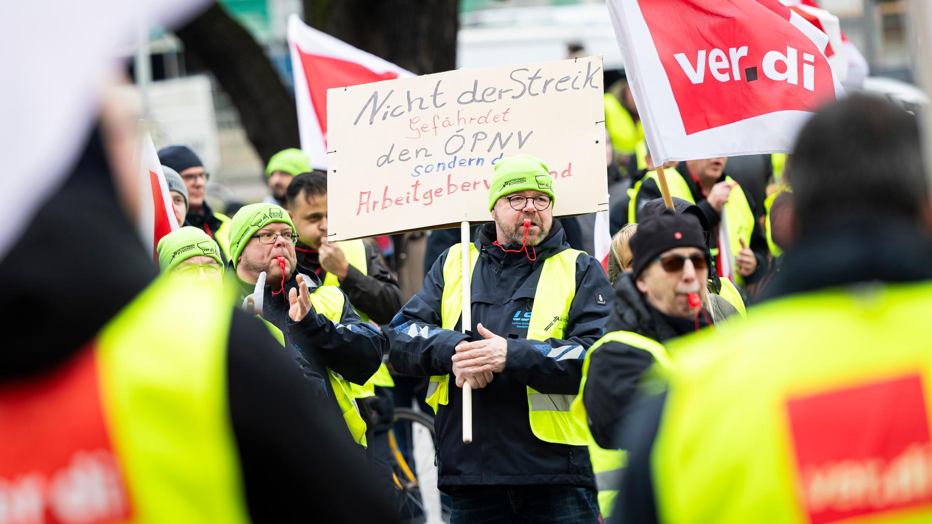 Ein Teilnehmer einer Verdi-Demonstration steht mit einem Schild mit der Aufschrift "Nicht der Streik gefährdet den ÖPNV, sondern der Arbeitgeberverband" während einer Kundgebung in der Innenstadt von Hannover. 