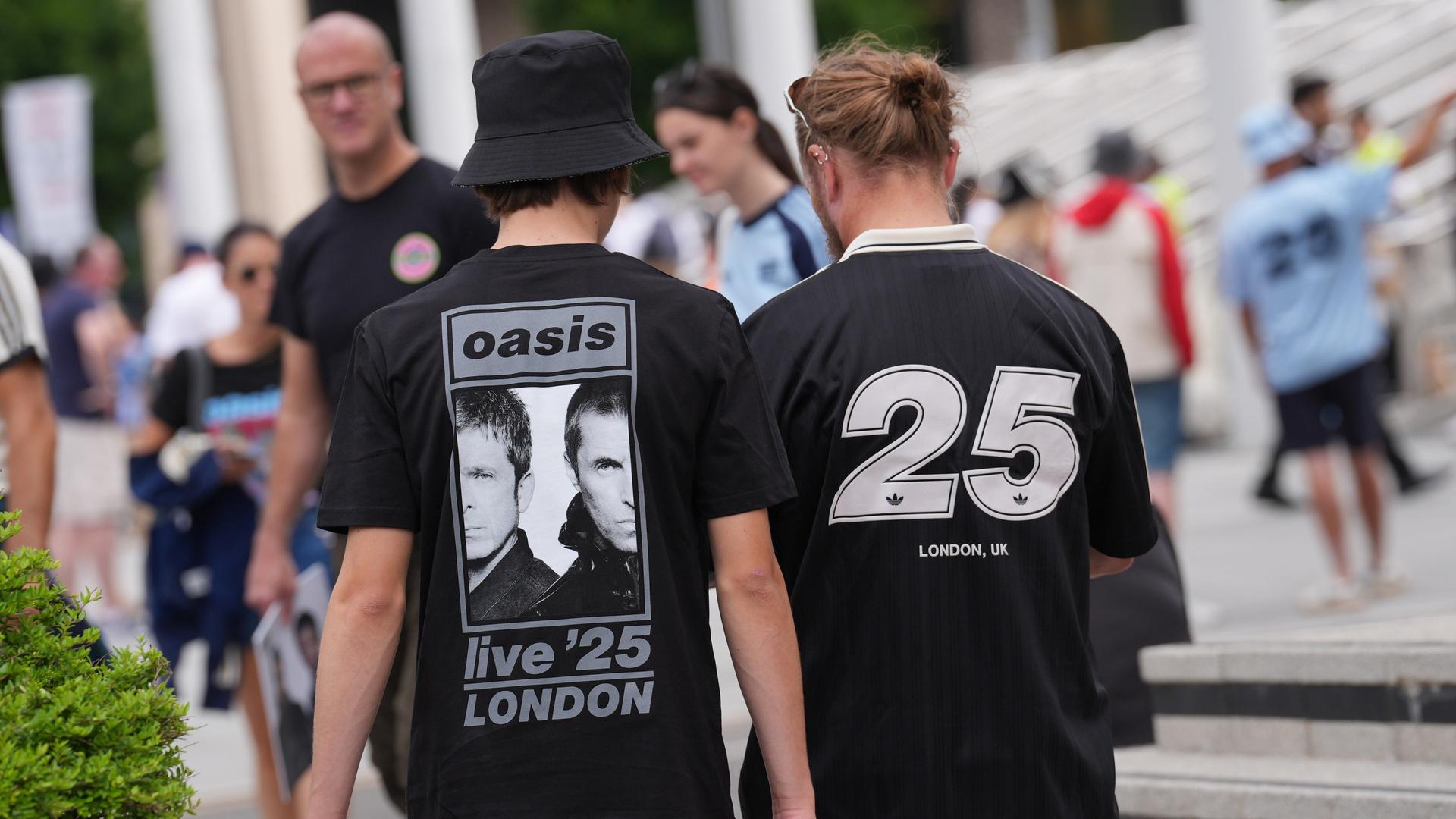 Fans außerhalb des Wembley-Stadions. Sie tragen T-Shirts mit der Aufschrift "Oasis - live '25 - London" Fans außerhalb des Wembley-Stadions. Sie tragen T-Shirts mit der Aufschrift "Oasis - live '25 - London"