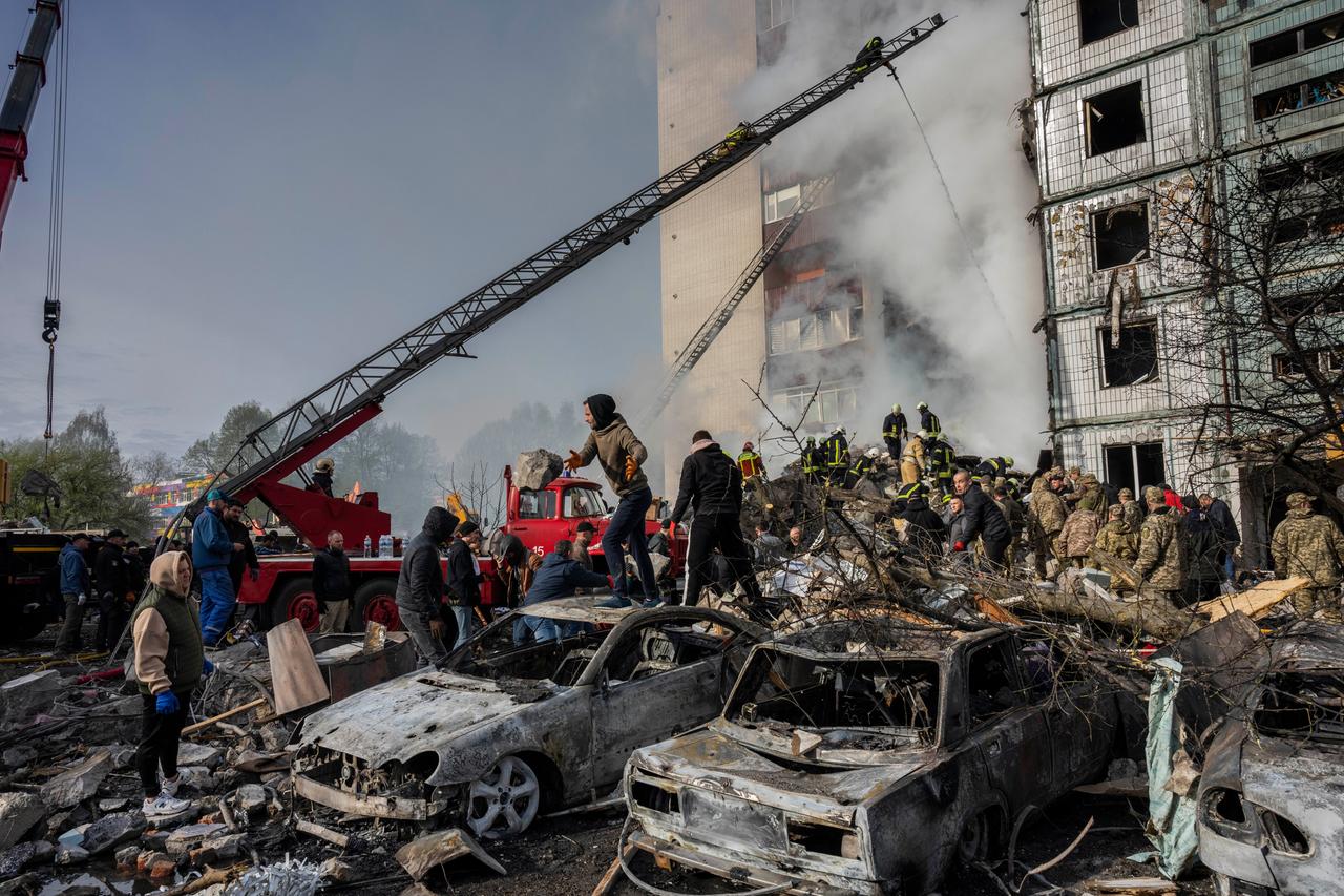 Aus einem Wohnblock in Uman in der Ukraine steigt Rauch aus. Die Fensterscheiben sind zerstört. Vor dem Haus stehen viele Menschen auf einem Schutthaufen. Es sind ausgebrannte Autos zu sehen.