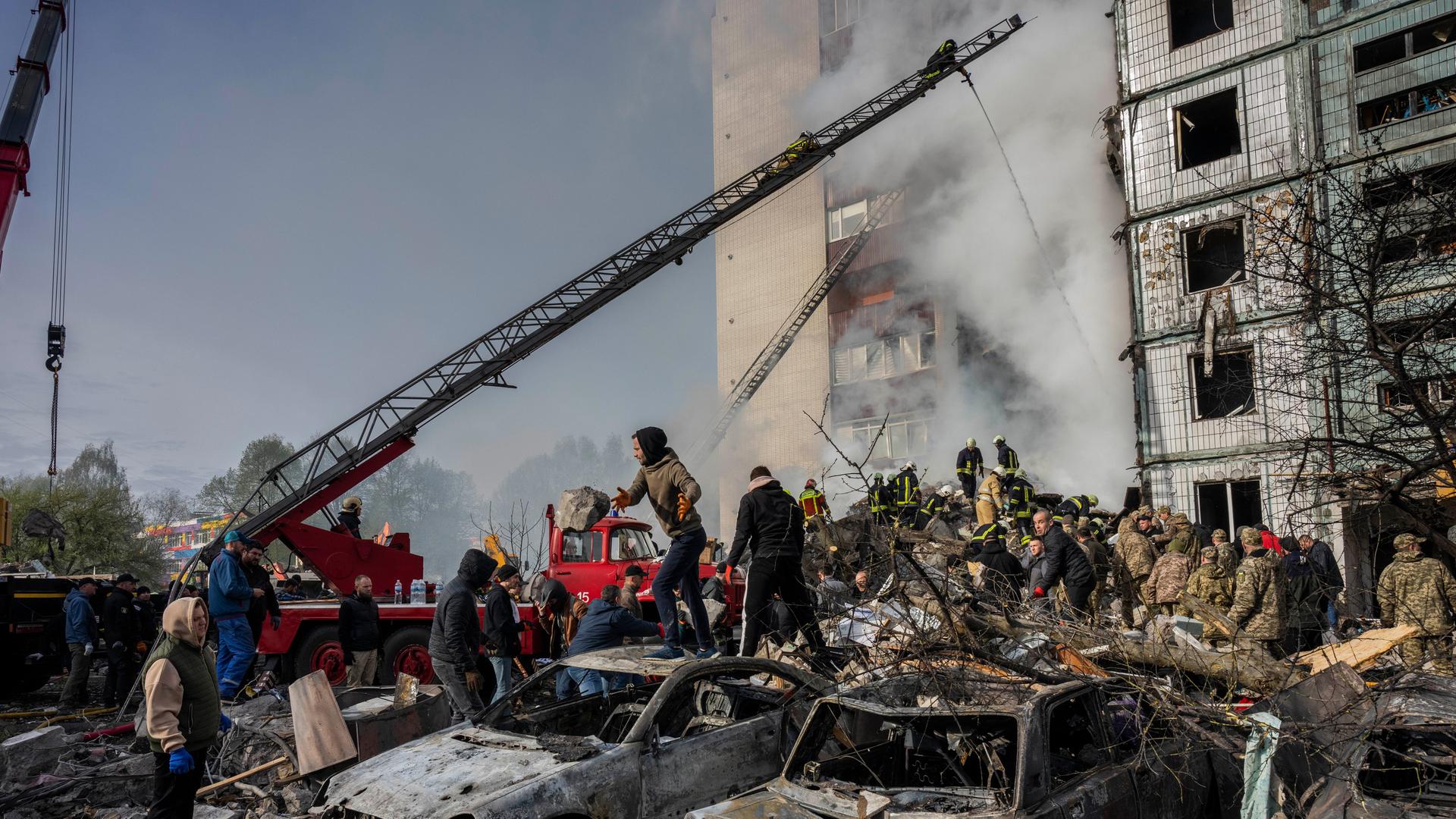 Aus einem Wohnblock in Uman in der Ukraine steigt Rauch aus. Die Fensterscheiben sind zerstört. Vor dem Haus stehen viele Menschen auf einem Schutthaufen. Es sind ausgebrannte Autos zu sehen. Aus einem Wohnblock in Uman in der Ukraine steigt Rauch aus. Die Fensterscheiben sind zerstört. Vor dem Haus stehen viele Menschen auf einem Schutthaufen. Es sind ausgebrannte Autos zu sehen.