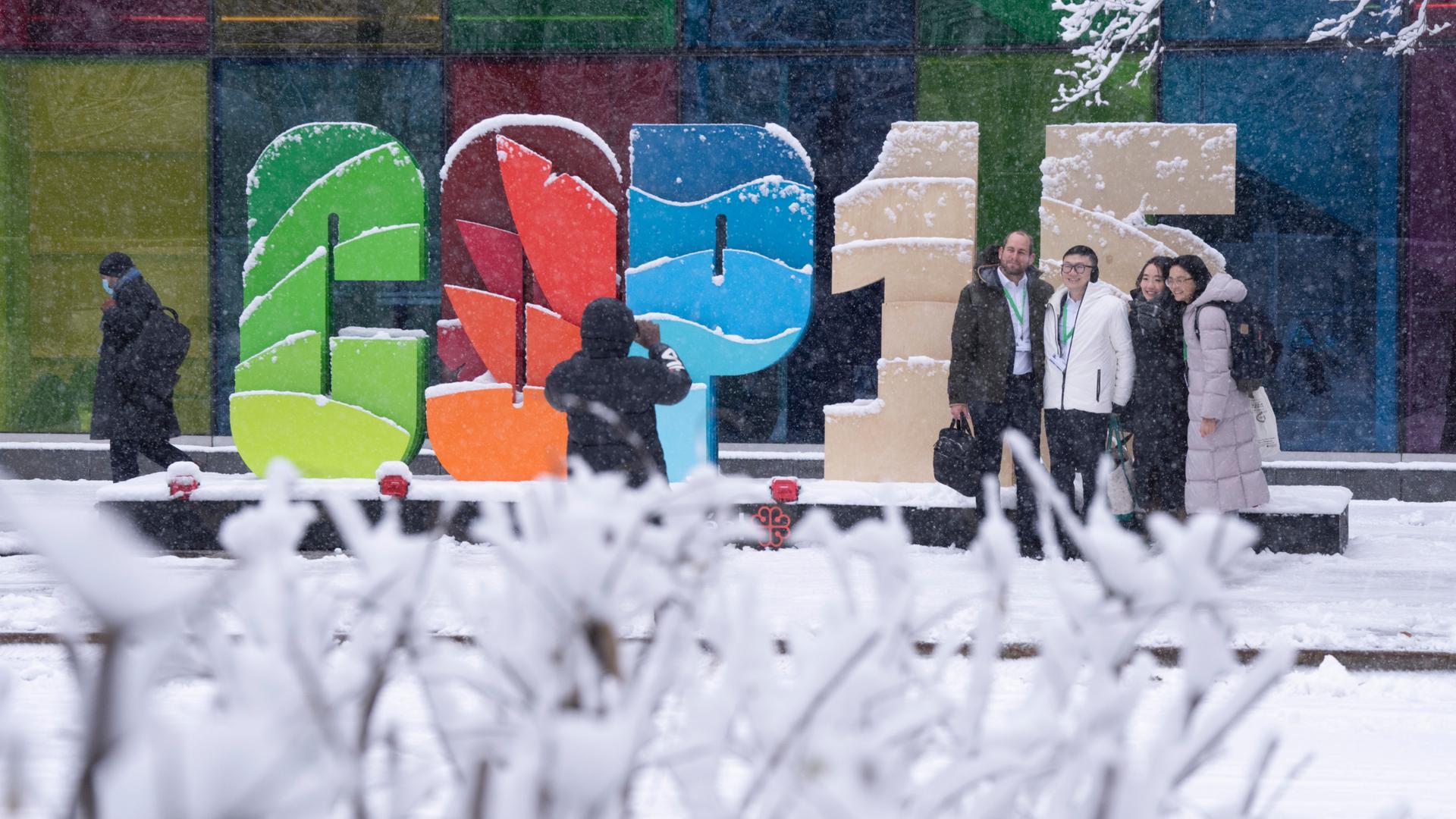 Delegierte auf der Weltnaturkonferenz in Montreal posieren vor einem Schild im Freien