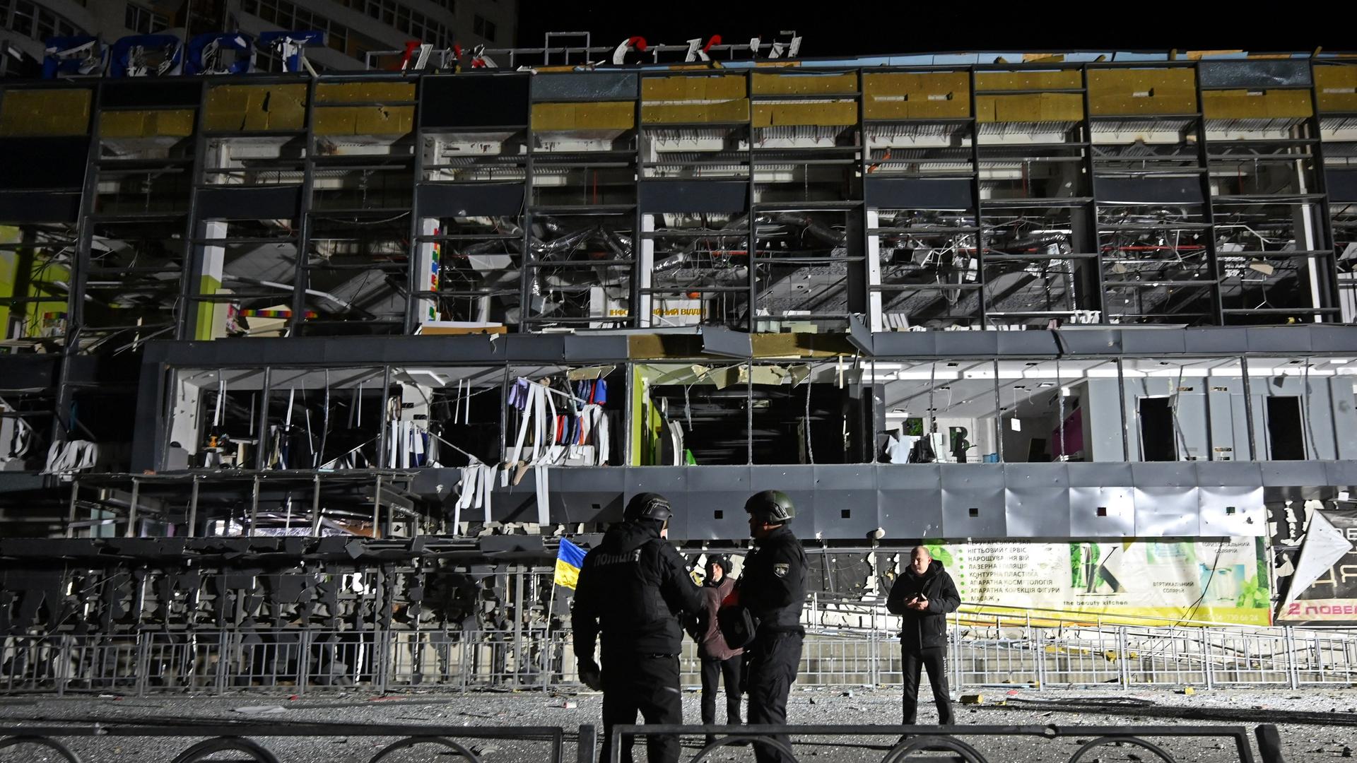 Ukrainische Polizisten stehen vor dem zerstörten Supermarkt in Charkiw.