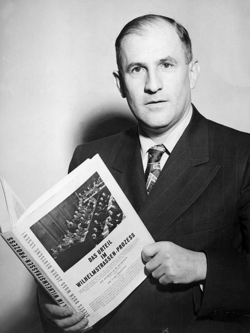 Porträt von Robert Kempner, der ein Buch mit der Aufschrift "Das Urteil im Wilhelmstraßen-Prozess" hält.