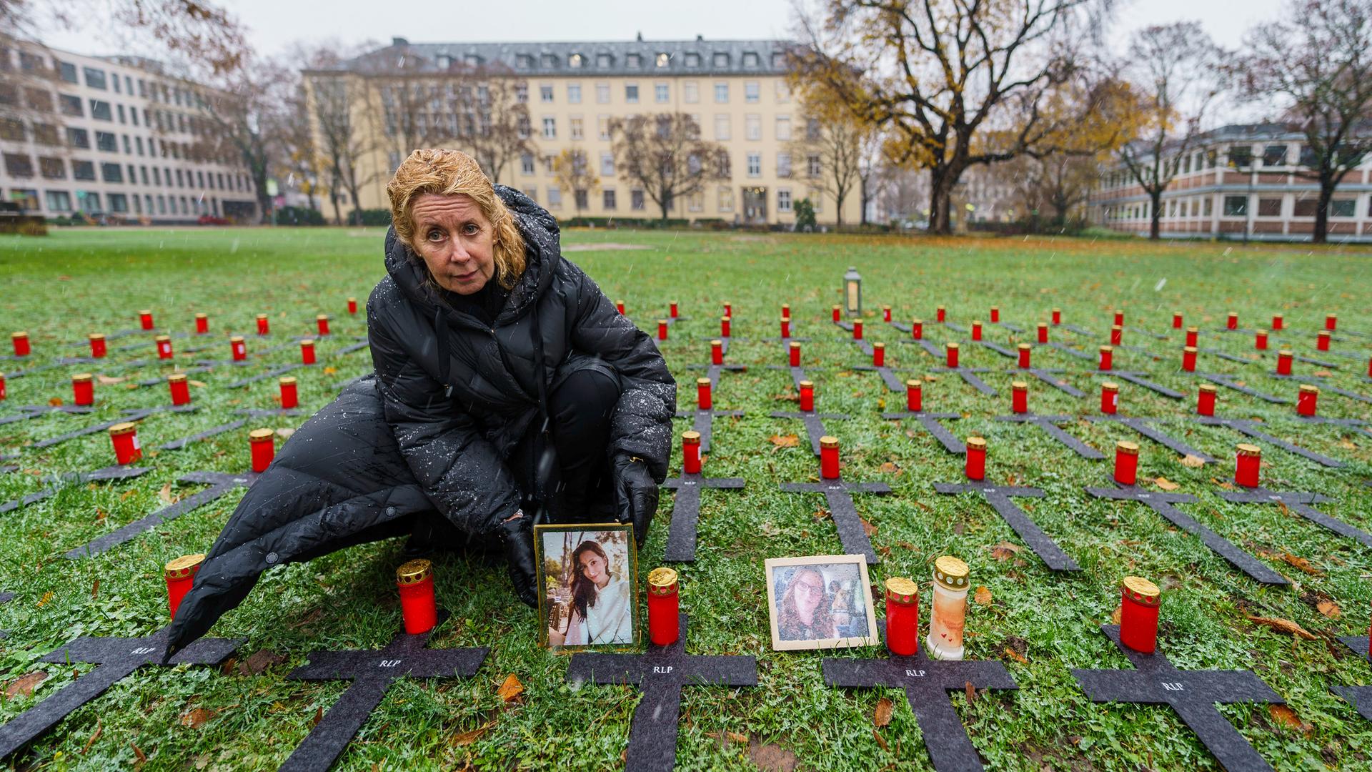 Inka Orth stellt auf einer Wiese, auf der mehrere schwarze Kreuze liegen, das Porträt ihrer verstorbenen Tochter Johanna neben eine Kerze ab.