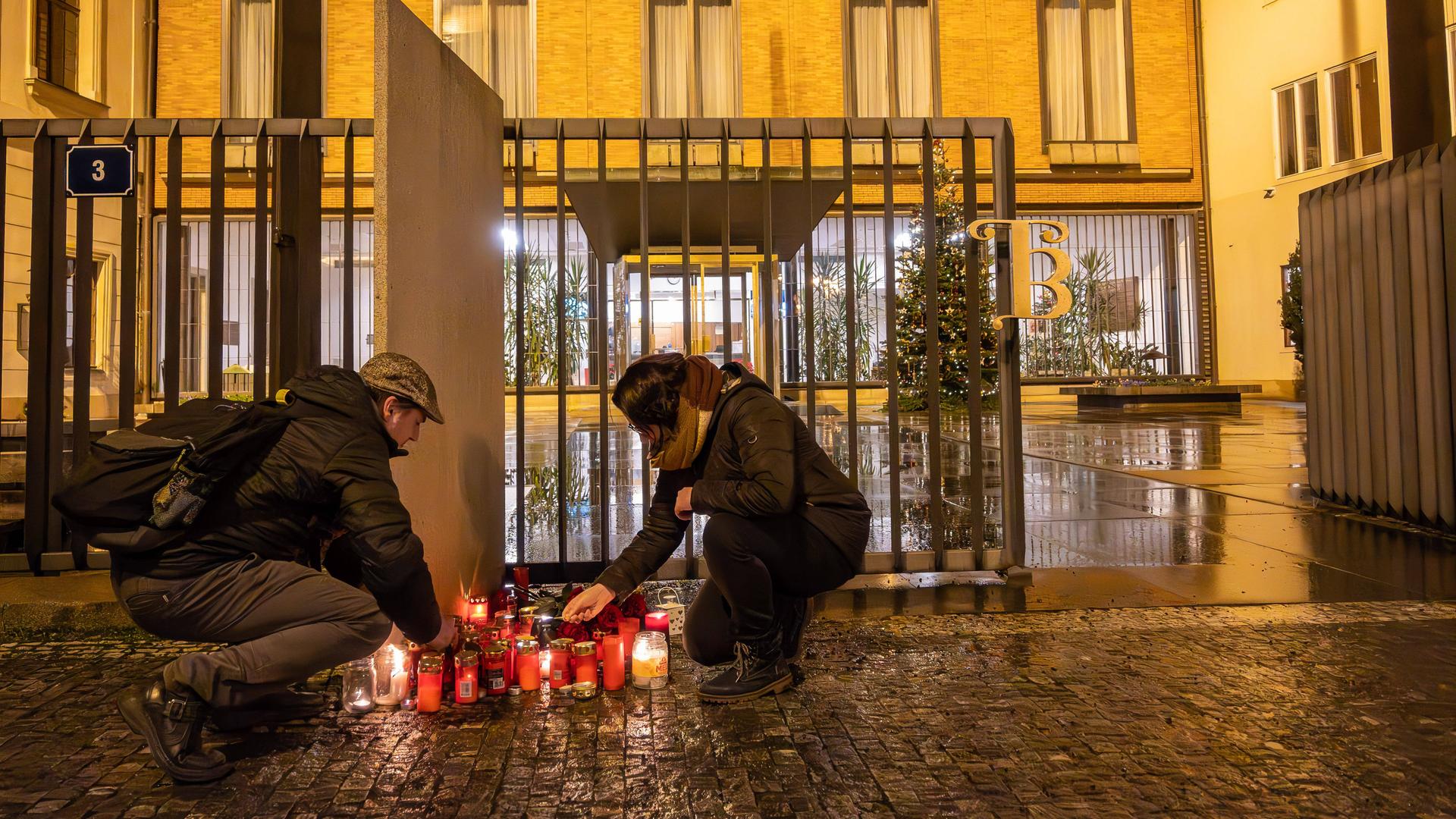 Menschen zünden in Prag vor einer Universität Kerzen an. 