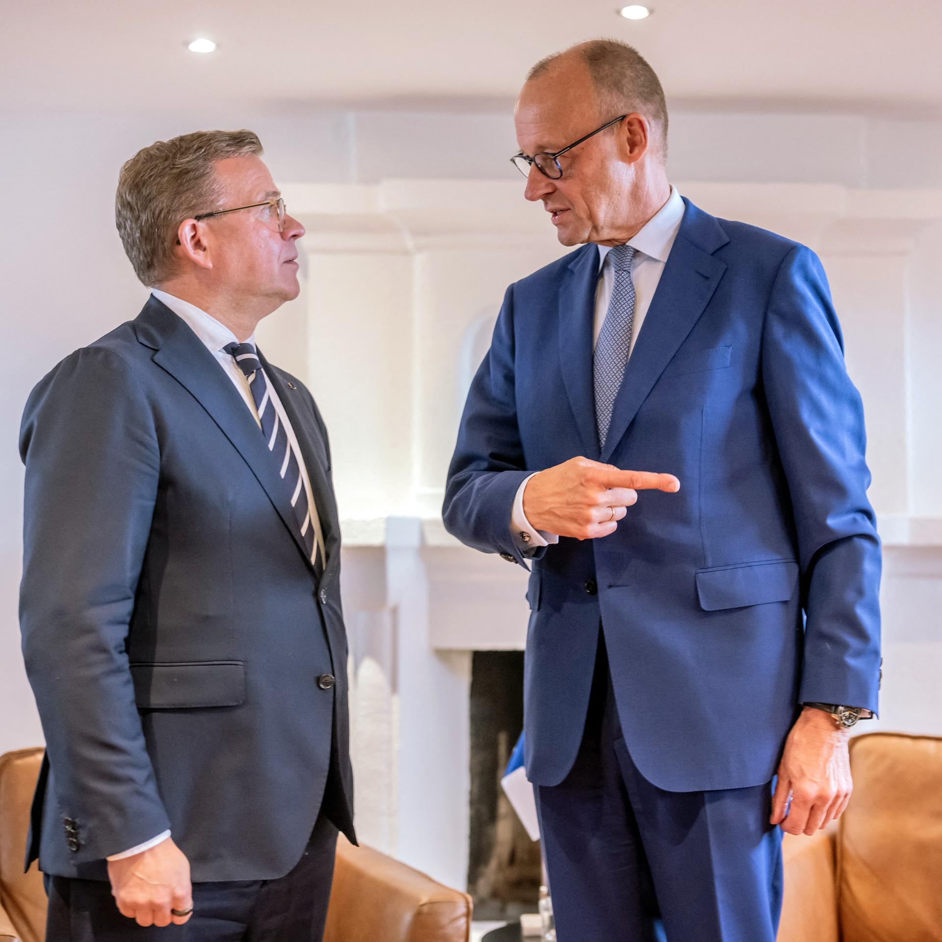 Bundeskanzler Friedrich Merz (CDU, r) steht neben Petteri Orpo, Ministerpräsident von Finnland. Merz zeigt mit seinem rechten Zeigefinger nach rechts aus dem Bild. 